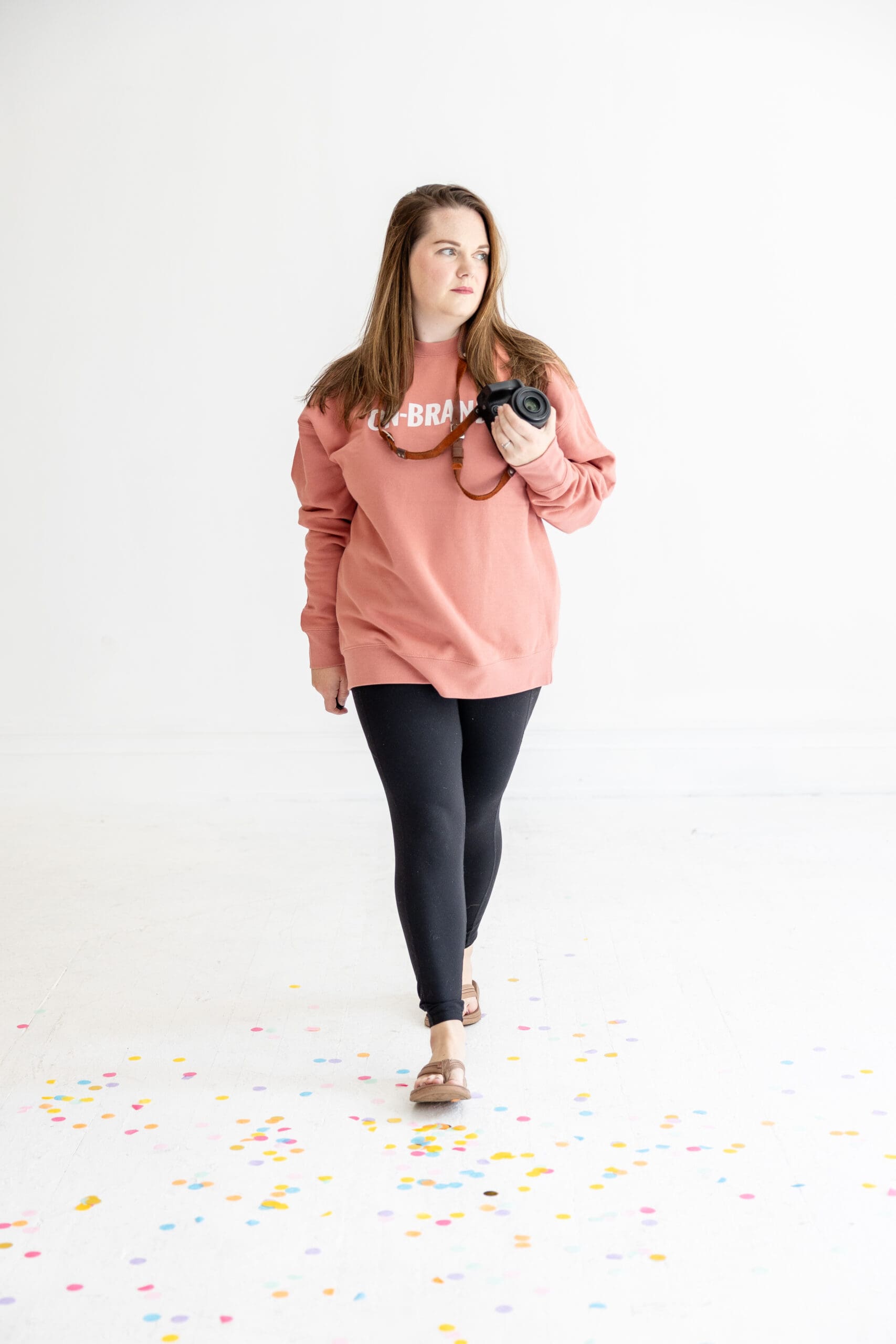 Woman holding camera walks across confetti-covered floor | What to wear for your brand photos | Kayla Petrosky Photography