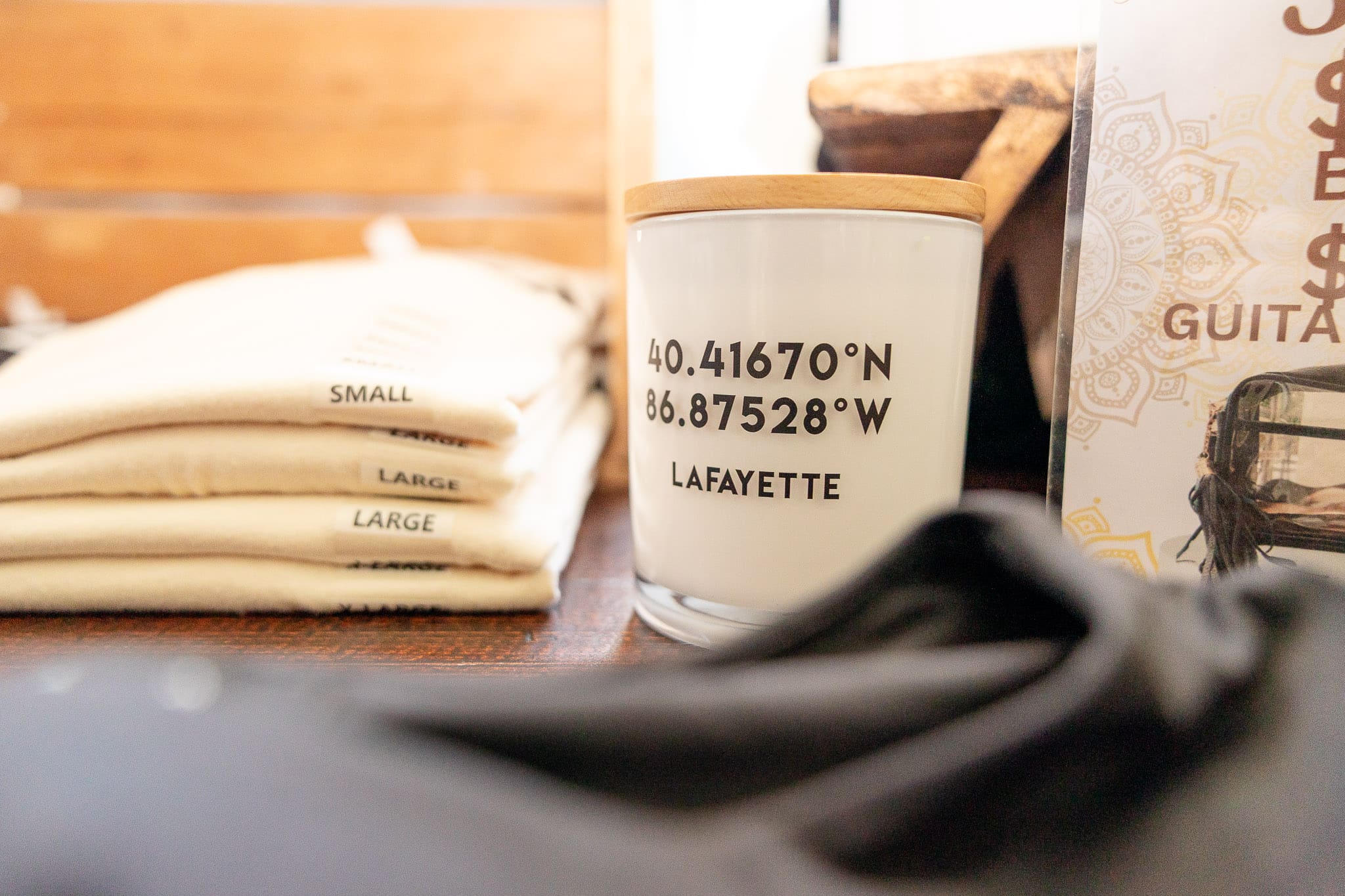 Candle with coordinates of Lafayette IN sits next to a folded pile of shirts | Shop small in Greater Lafayette, Indiana | Kayla Petrosky Photography