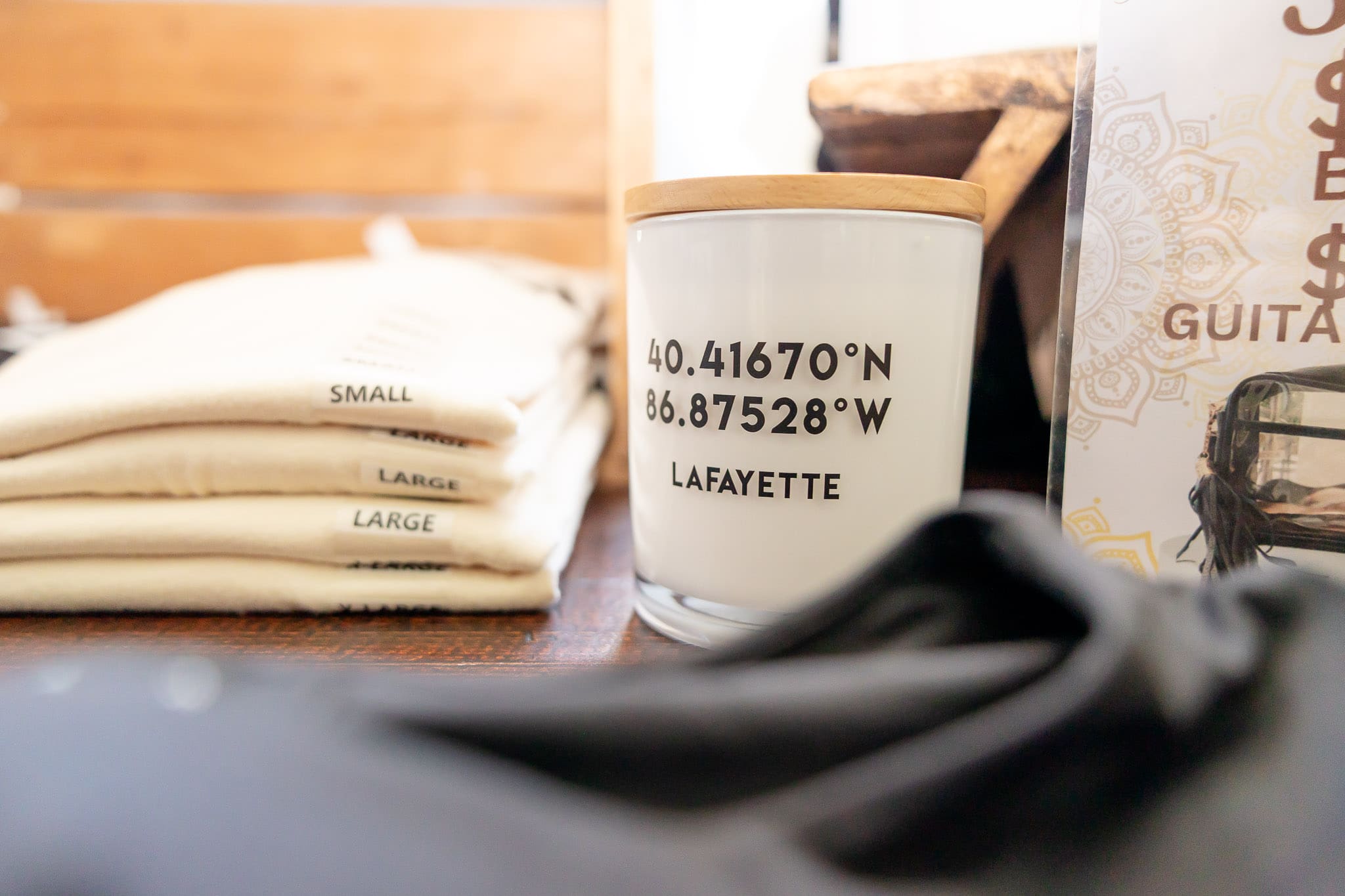 Pile of cream shirts next to a candle with geographic coordinates of the local town | 5 Photos Every Small Business Needs | Kayla Petrosky Photography