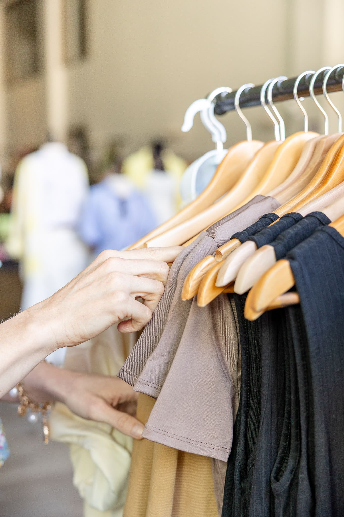 Hand rifles through hangers of boutique clothing | Brand photos are best alternative to stock photos