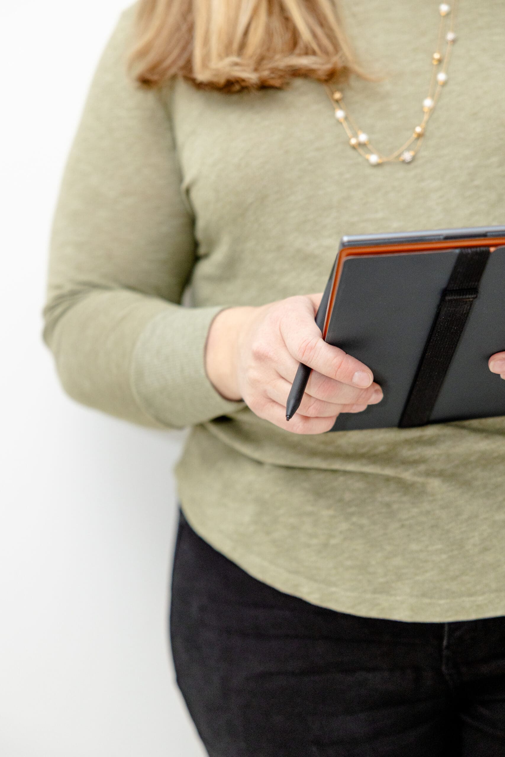 Person in green sweater holds tablet and pen | Brand photos are best alternative to stock photos