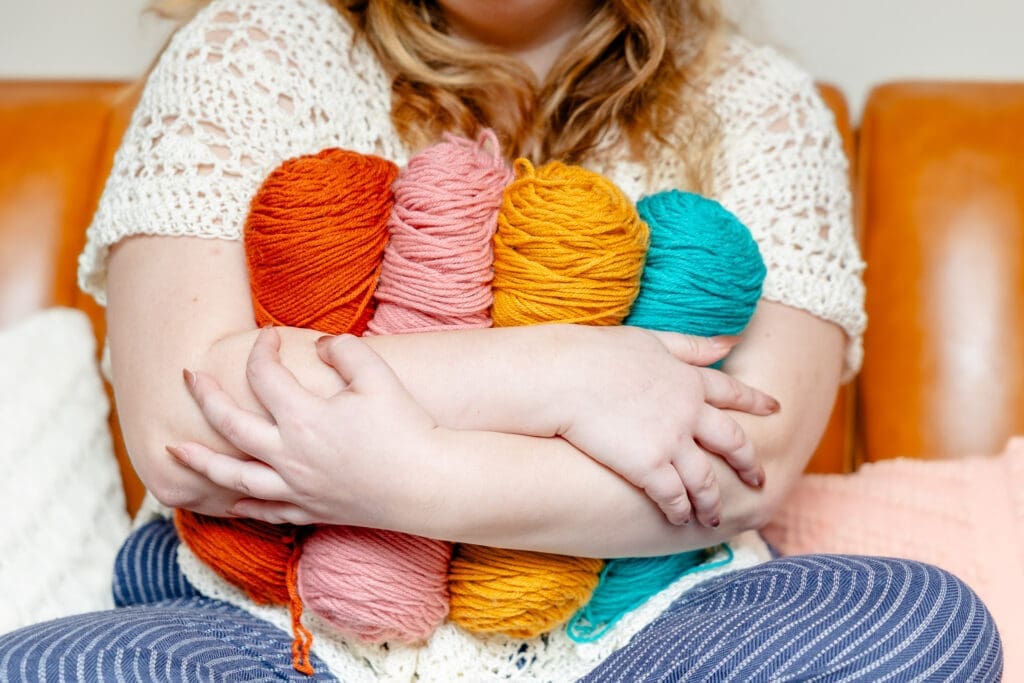 Person wearing crocheted top hugs brightly colored yarn | Fiber Artist Brand Photos | Kayla Petrosky Photography