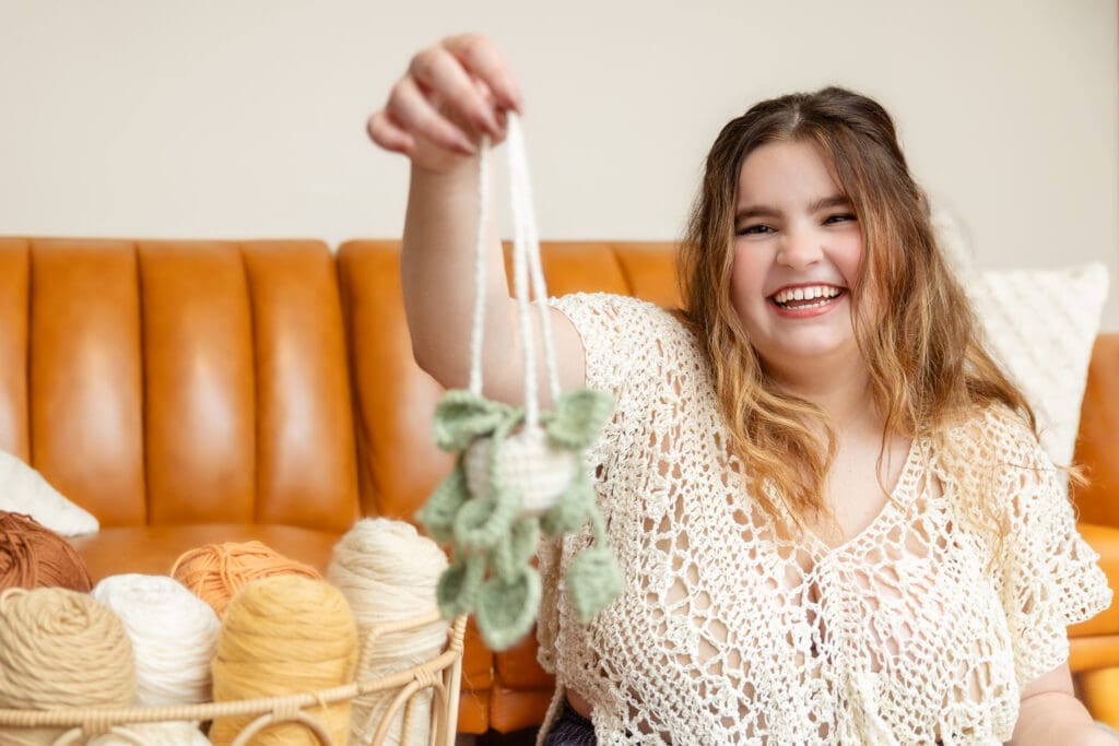 Woman in crochet top holds out crocheted hanging plant | Fiber Artist Brand Photos | Kayla Petrosky Photography