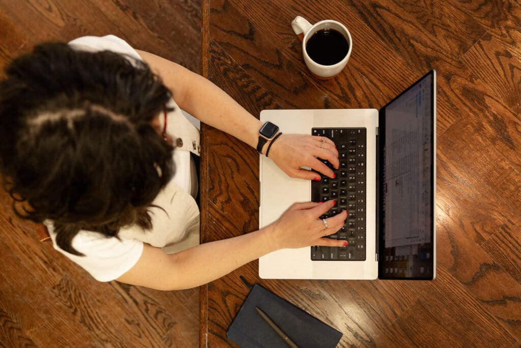 Top down view of woman working at laptop with cup of coffee and notebook | Indiana Perinatal Therapist Brand Photos | Kayla Petrosky Photography