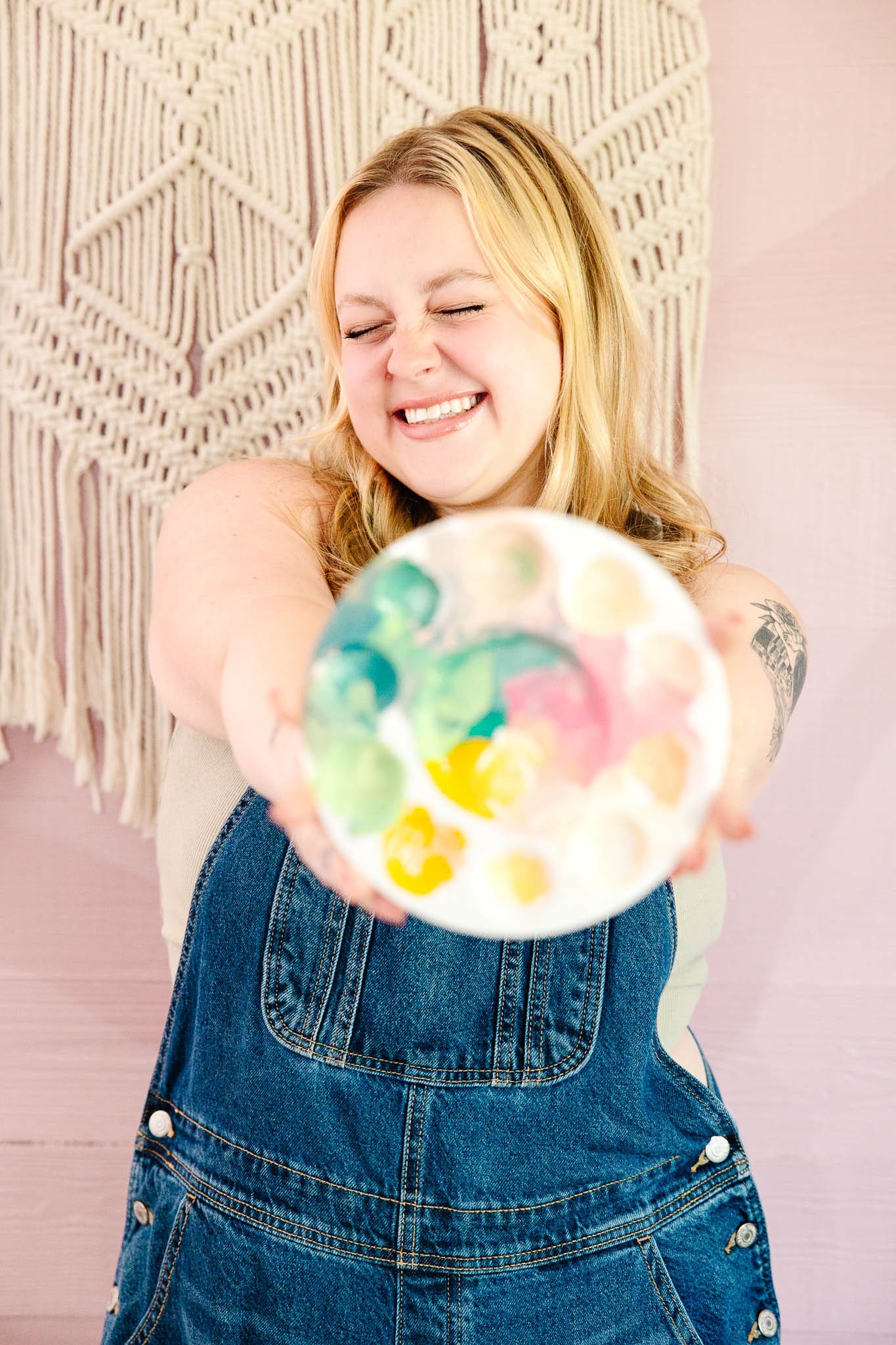 Woman in overalls smiles while holding out a paint palette | Brand Photo Process | Kayla Petrosky Photography