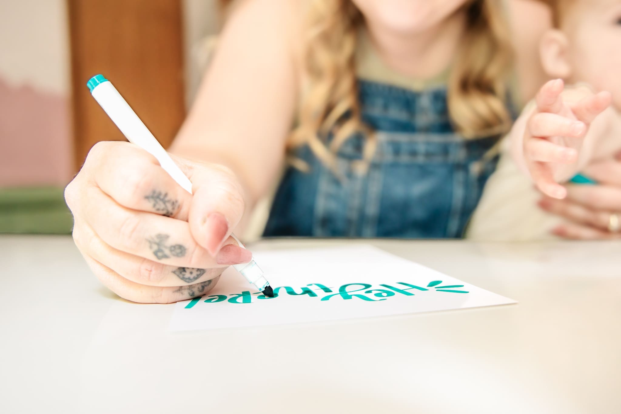 Person writes artistic note on a card while holding a baby | Brand photos with Lafayette Lettering | Kayla Petrosky Photography