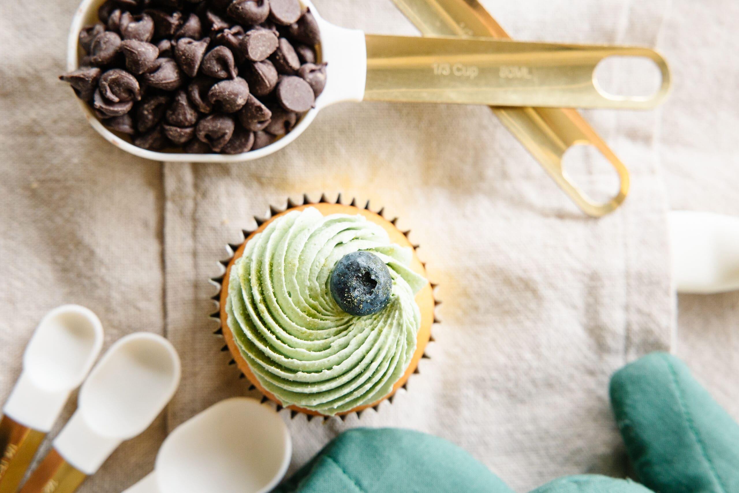 Array of baking supplies and ingredients, plus a cupcake with green icing | Bakery Brand Photos | Kayla Petrosky Photography