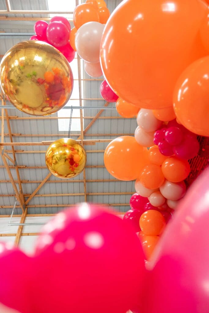 Bright orange, pink, and gold balloons backdrop